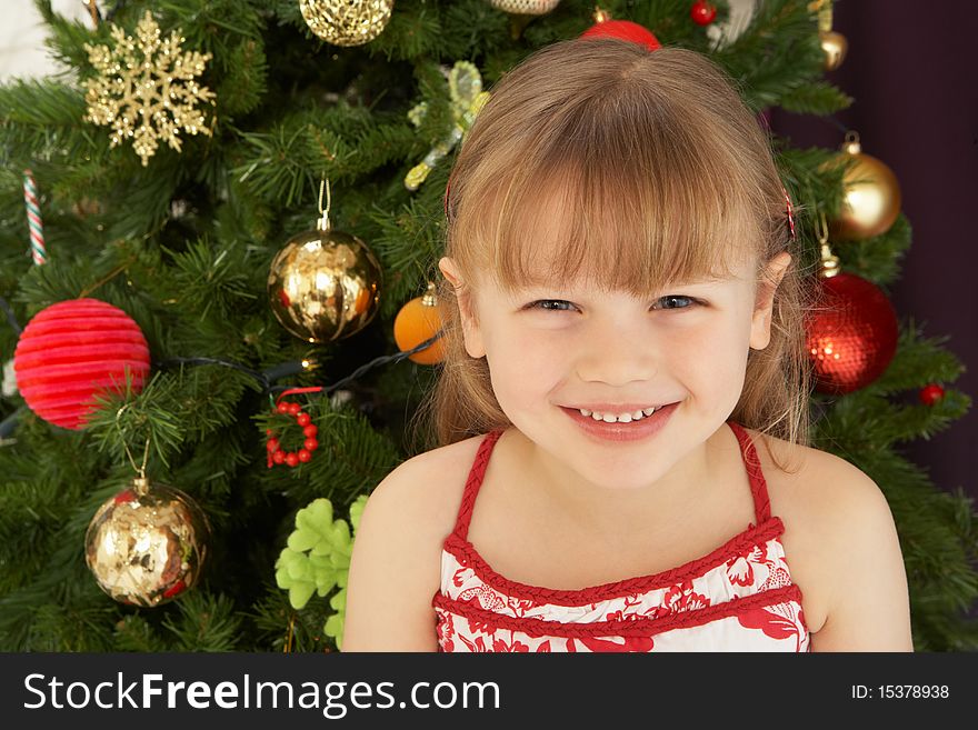 Young Girl Decorating Christmas Tree Smiling At Camera