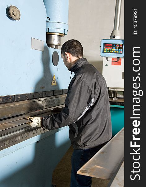 Metalworker at work in his workshop forging the iron with a machine. Metalworker at work in his workshop forging the iron with a machine