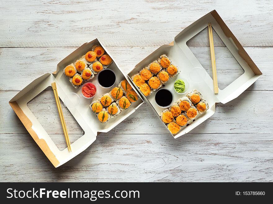 Two sushi set in a box on a wooden table. Street food. Top view.