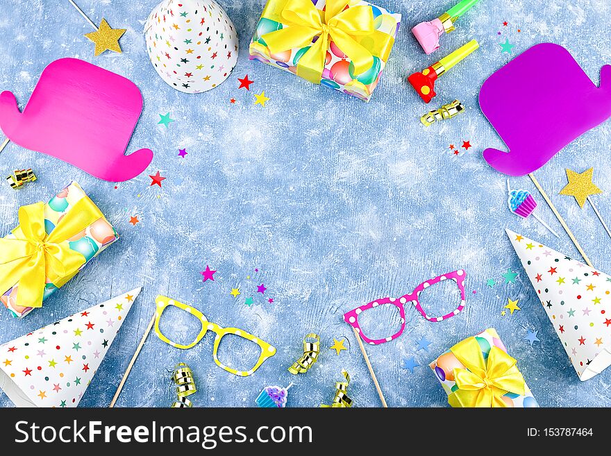 Birthday party accessories and event supplies background with wrapped gifts, confetti, balloons, party hats, decorations, copy space. Birthday party accessories and event supplies background with wrapped gifts, confetti, balloons, party hats, decorations, copy space