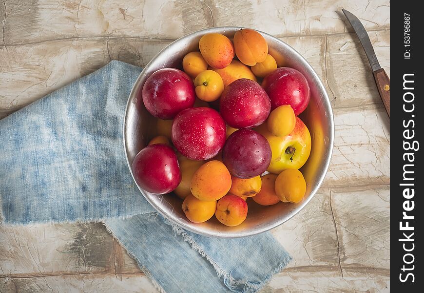 Fresh fruit nectarines, cream and apricots in a round plate on a denim napkin, the composition on a bright table