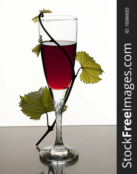 A glass of red wine on a white background and the vine. A glass of red wine on a white background and the vine