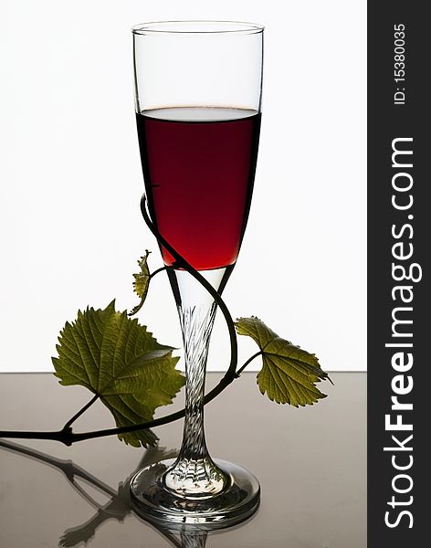 A glass of red wine on a white background and the vine. A glass of red wine on a white background and the vine.