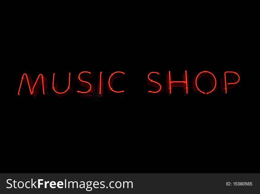 Red neon sign of the word 'MUSIC SHOP' on a black background. Red neon sign of the word 'MUSIC SHOP' on a black background.