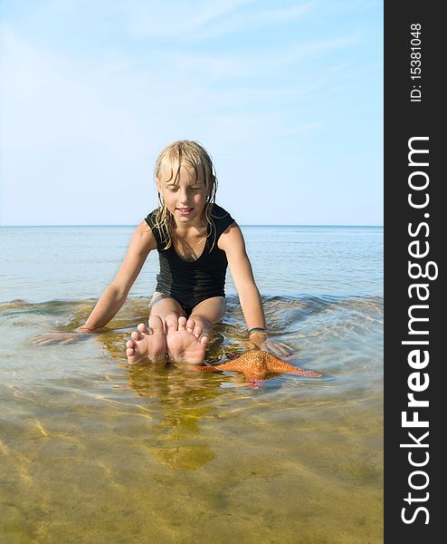 Vertical photo with girl and starfish in the sea`s water. Vertical photo with girl and starfish in the sea`s water.