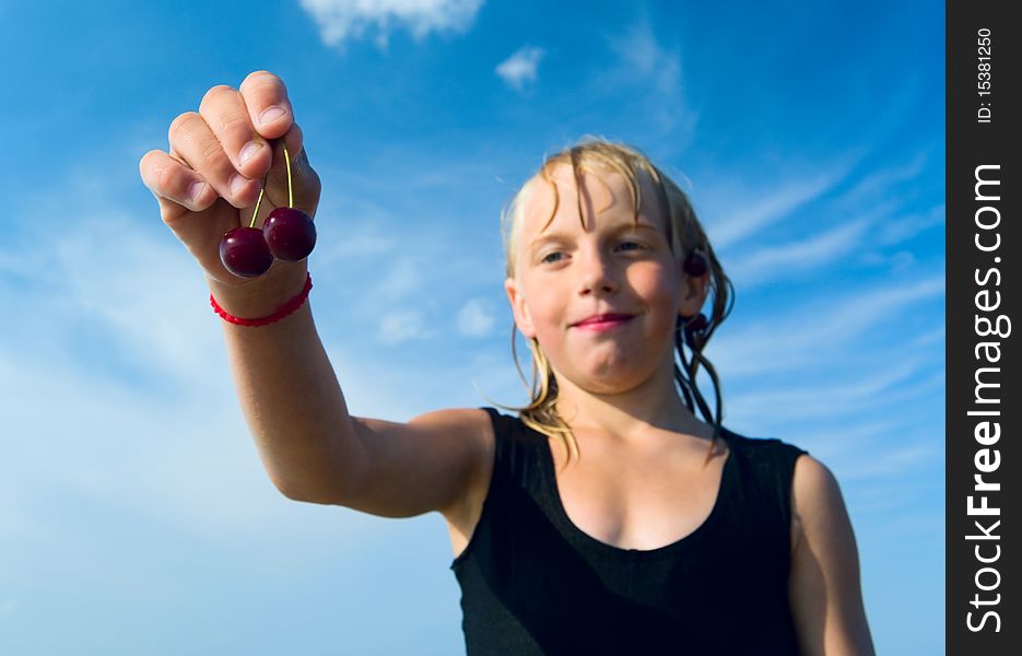 Focus is on the hand with cherry, wet girl on the blue sky background. Focus is on the hand with cherry, wet girl on the blue sky background.