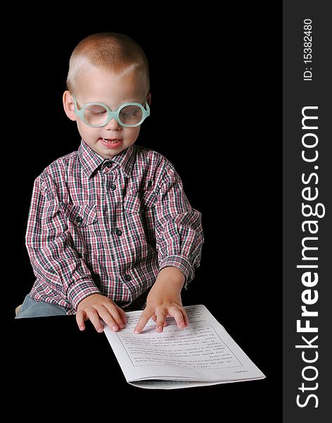 Cute boy with glasses pointing at paper isolated on a black background