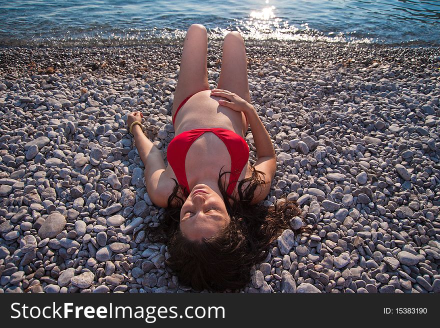 Young, pregnant woman, lying on the beach, relaxing and enjoying the sun at sunset. Young, pregnant woman, lying on the beach, relaxing and enjoying the sun at sunset