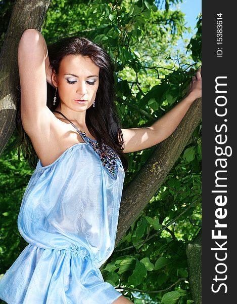 Fashion shoot of a young brunette girl in a light colorful dress. The image is taken outdoors, on a nature background with trees and water. Fashion shoot of a young brunette girl in a light colorful dress. The image is taken outdoors, on a nature background with trees and water.
