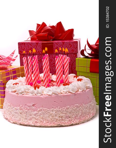 Pink pie with eleven candles and gifts in boxes on a white background