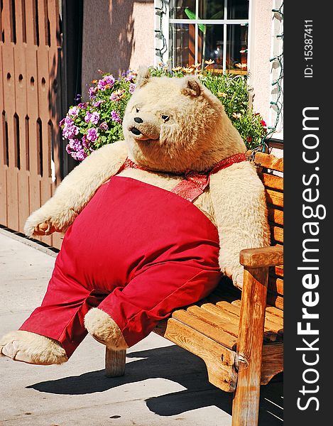 Big teddy bear in red pants sitting on bench. Big teddy bear in red pants sitting on bench