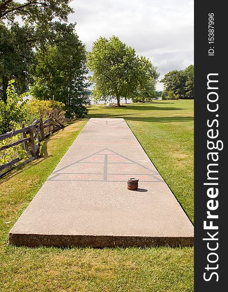 A concrete shuffleboard court in a grassy area at a lakeside resort.