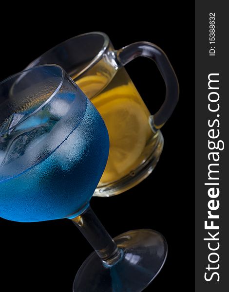 Ice tea and a blue drink with ice in a glass on a black background. Ice tea and a blue drink with ice in a glass on a black background