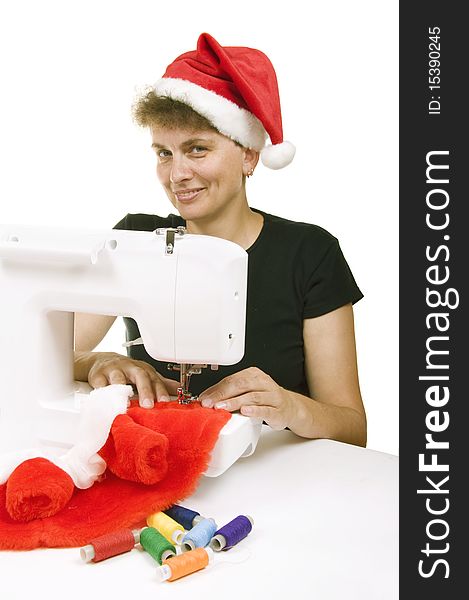 Woman sewing a fur coat for Santa Claus on the sewing machine