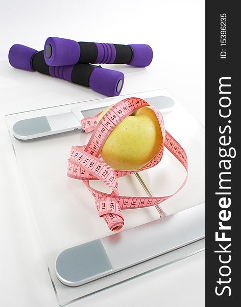 Apple tighten with measure tape, dumbbell, and scale isolated on white