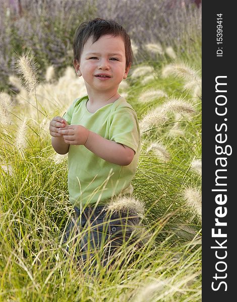 A small child standing in a long grass in a Mediterranean garden. A small child standing in a long grass in a Mediterranean garden.