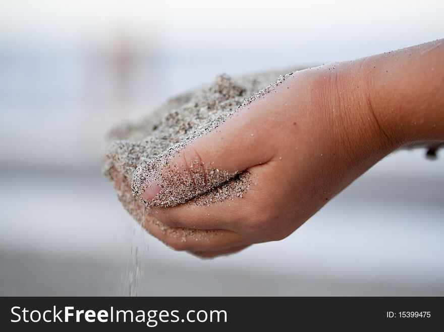 Child Holding Sand In The Hands