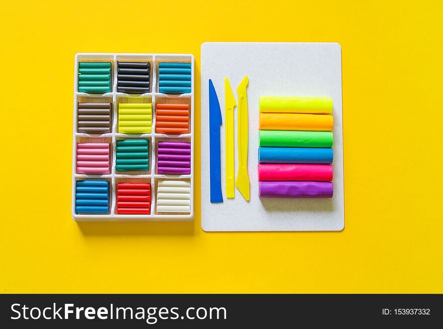 Stationery flat lay.Plasticine rainbow color stack and plastic board. Back to school. yellow background. kid child