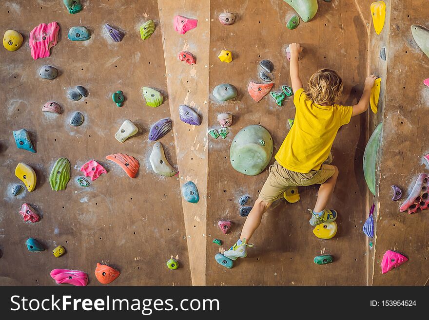 Little boy climbing a rock wall in special boots. indoor