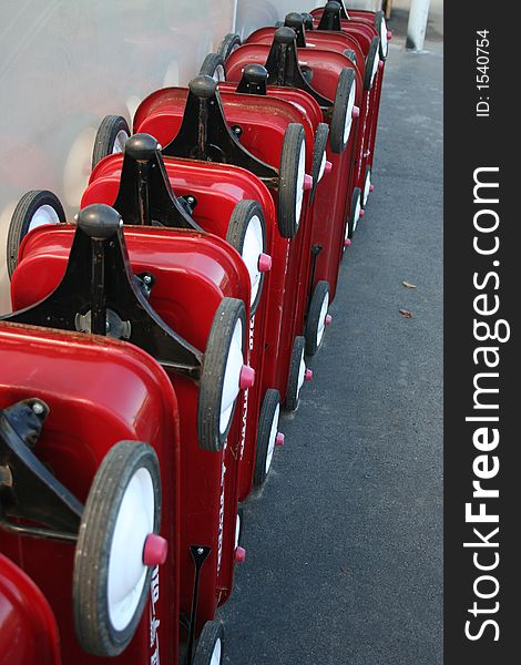 Red wagons and wheels lined up in a row outside