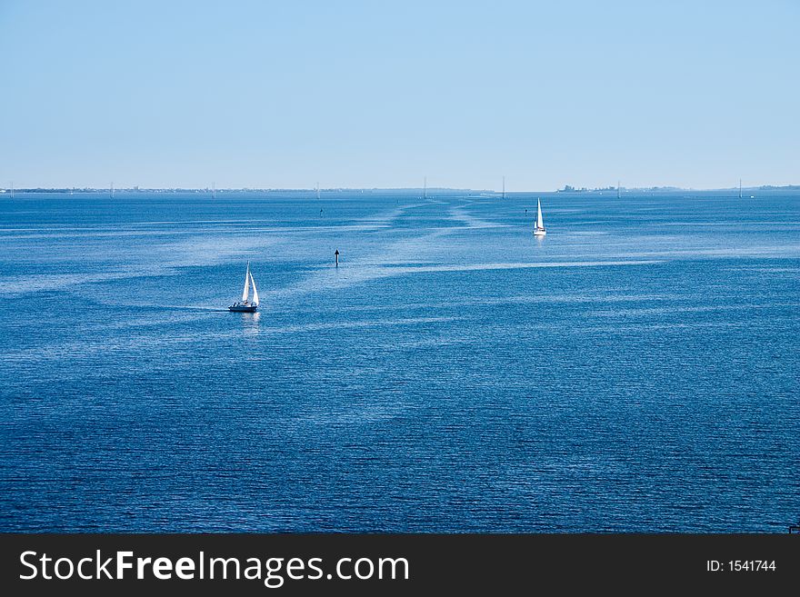 Calm waterscape with sailboats and patterns from passing boats