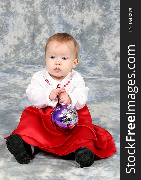 Little Baby Girl in Christmas dress with bulb in hand