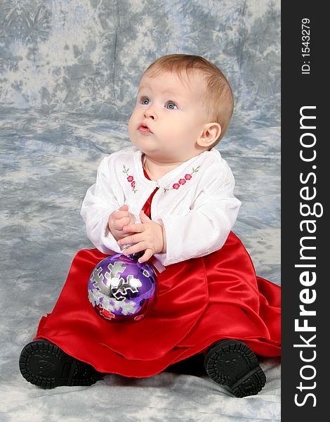 Little Baby Girl in Christmas dress with bulb in hand