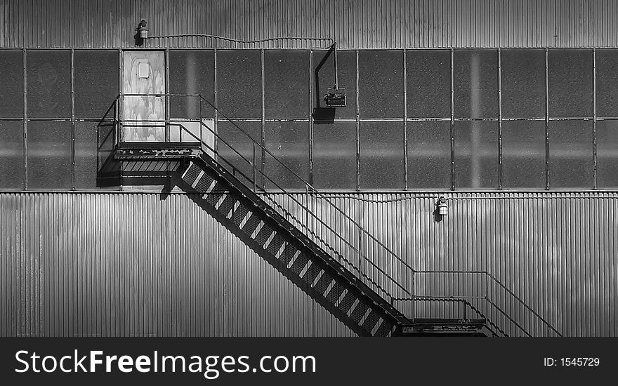 Black and white outside stairs, made from metal and leading to a rusty door.