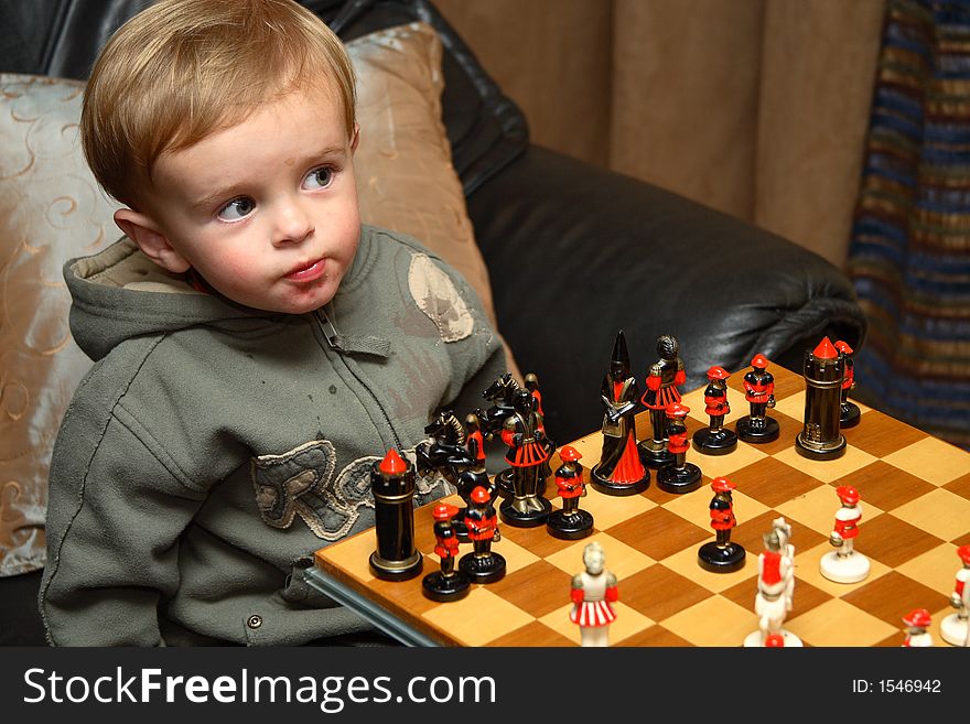 Young boy playing chess with his grandfather with focus on the boy