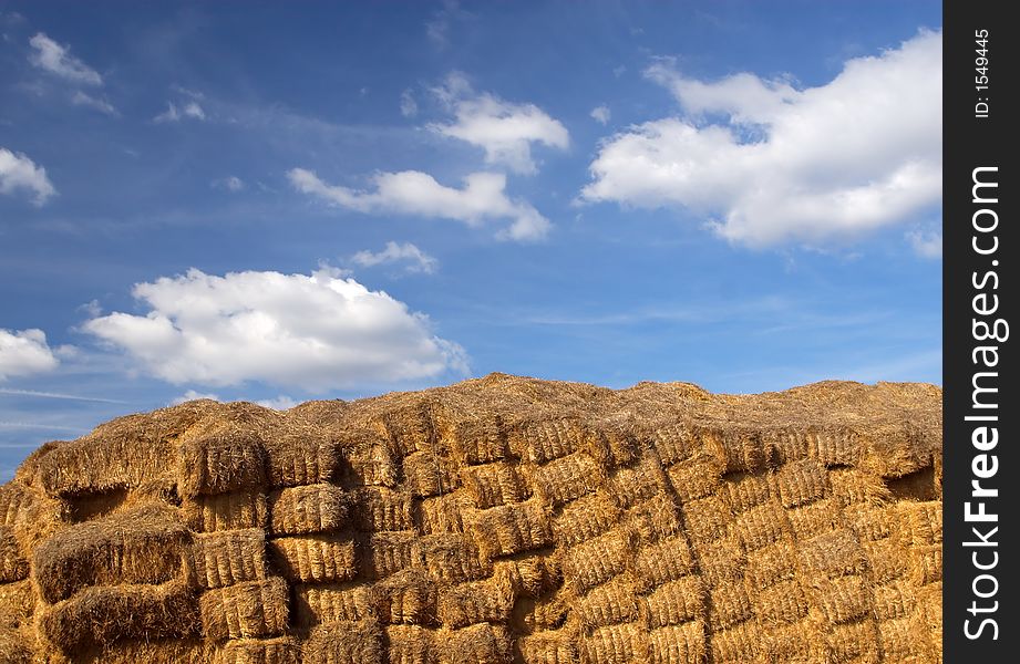 Wall of hay bales against a blue sky