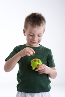 Little Boy Depositing Money In His Piggy Bank. Royalty Free Stock Photography