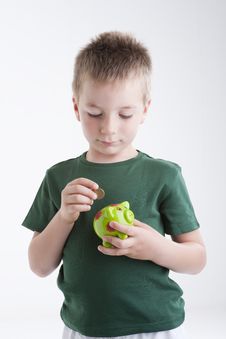 Little Boy Depositing Money In His Piggy Bank. Royalty Free Stock Photo