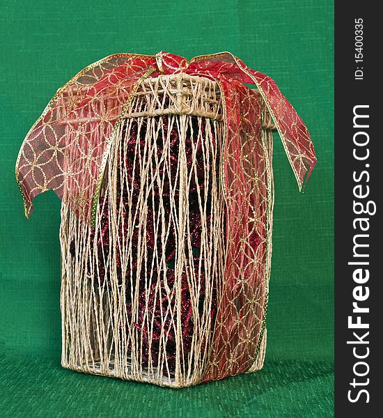 Straw Decorative box with red and gold ribbon on a green textile