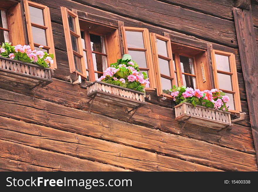 Wooden house with lovely flower boxes with pink geraniums. Wooden house with lovely flower boxes with pink geraniums