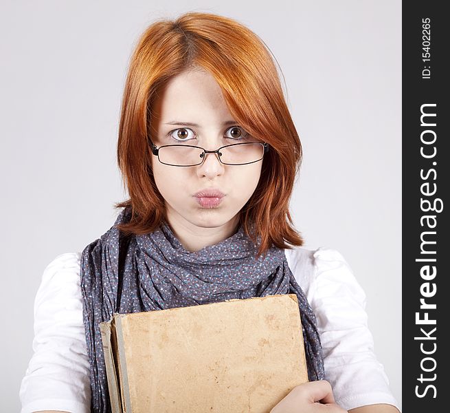 Young doubting fashion girl in glasses with old book