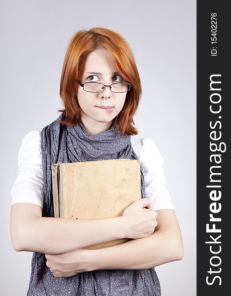 Young doubting fashion girl in glasses with old book