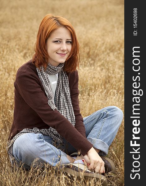Beautiful Red-haired Girl At Yellow Autumn Grass.