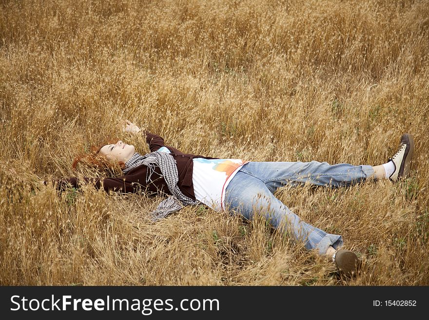 Young beautiful girl lying at yellow autumn field. Outdoor photo.