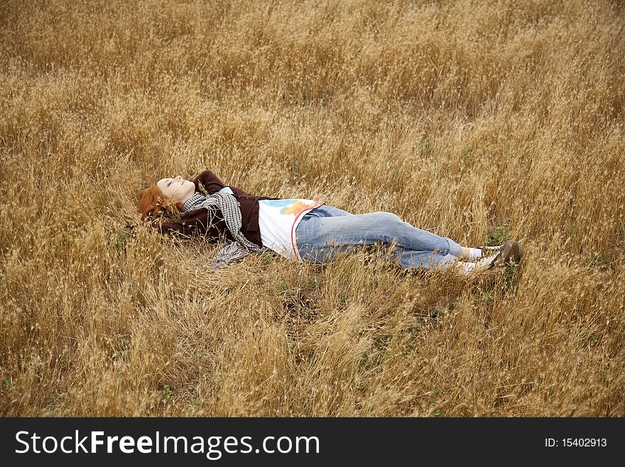 Young beautiful girl lying at yellow autumn field. Outdoor photo.