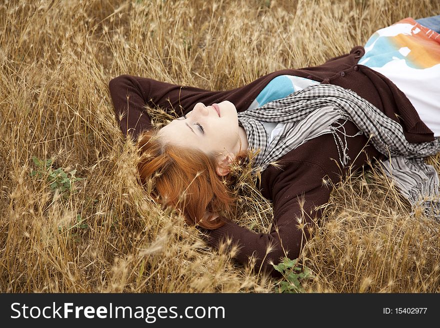 Young beautiful girl lying at yellow autumn field. Outdoor photo.