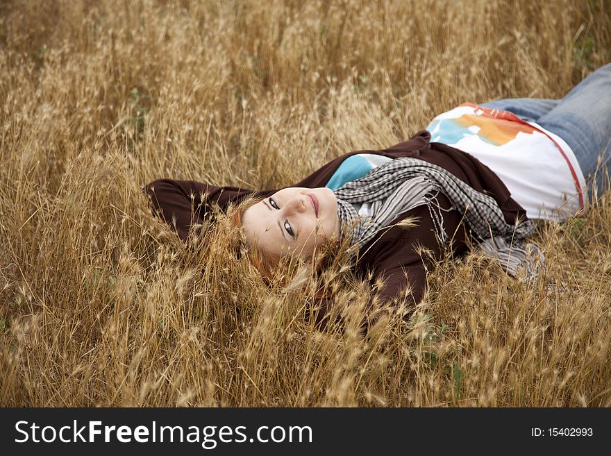 Young beautiful girl lying at yellow autumn field.