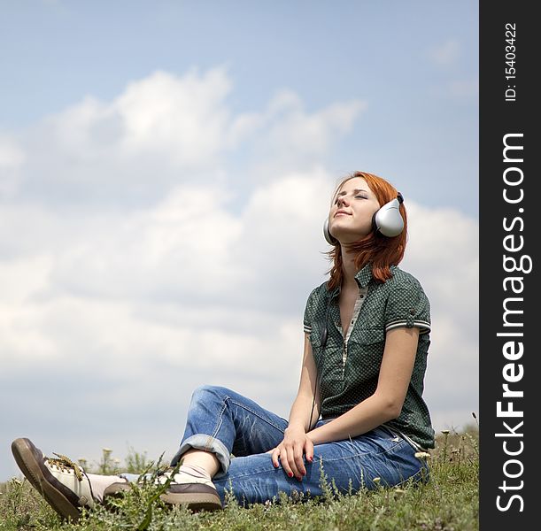 Young Girl With Headphones Sitting At Grasss.