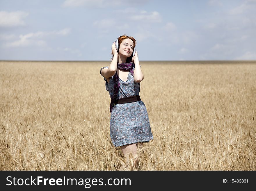 Young  smiling girl with headphones at field.