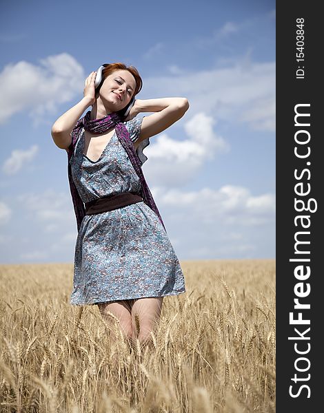 Young  smiling girl with headphones at field. Outdoor photo.