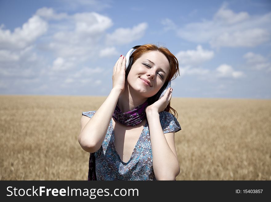 Young  smiling girl with headphones at field. Outdoor photo.