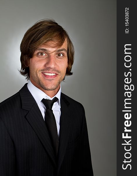 Young fresh confident businessman with longer hair over a greyish background. Young fresh confident businessman with longer hair over a greyish background.