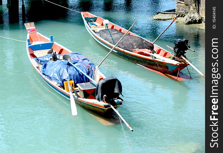 Picture two small fishing boat floating on the sea shore.