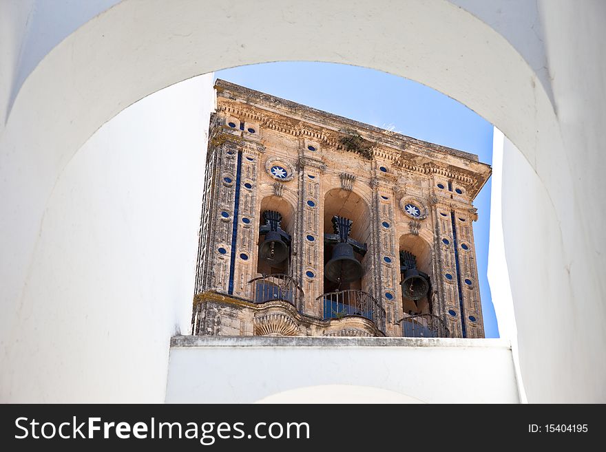 Santa Maria church bell tower framed by a white arch in Arcos de la Frontera, Cadiz - Spain