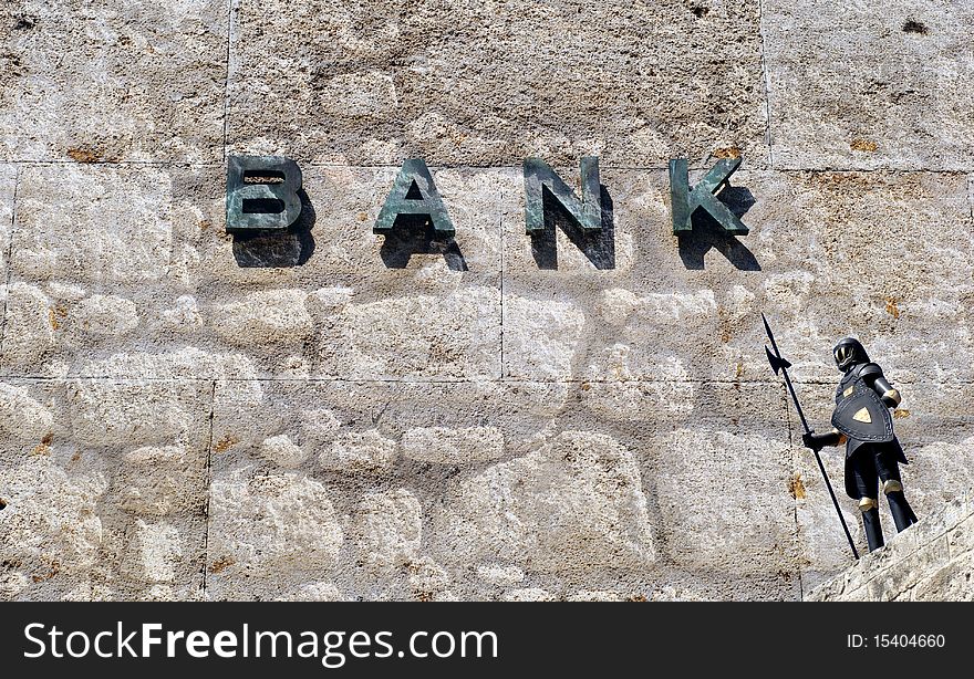 Bank sign on old wall protected by knight in armor. Bank sign on old wall protected by knight in armor.