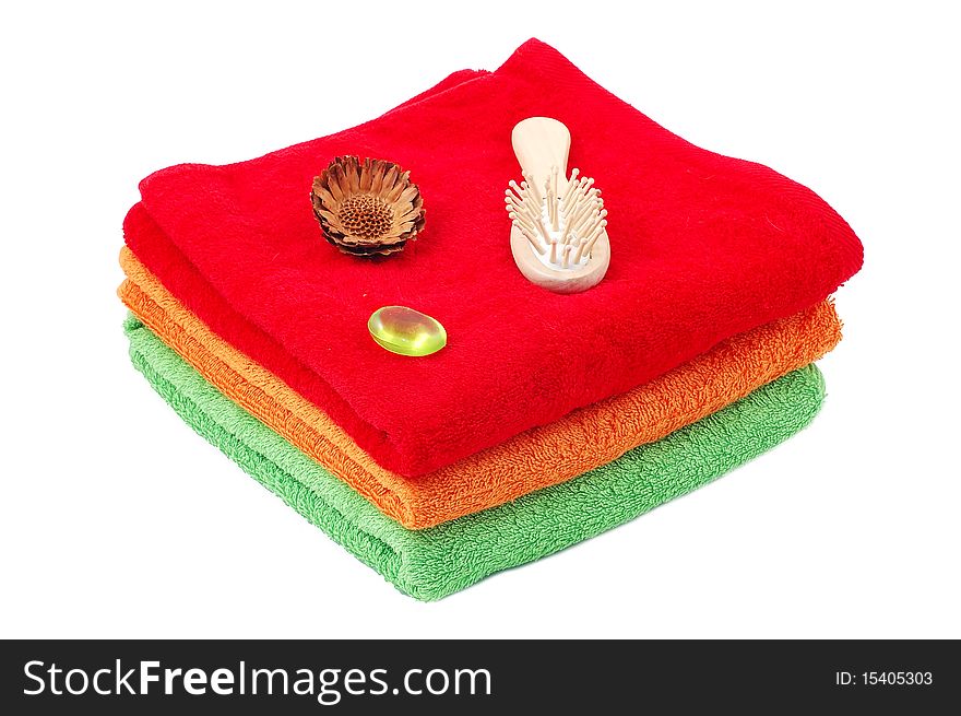 Bright fluffy towels a hairbrush on a white background